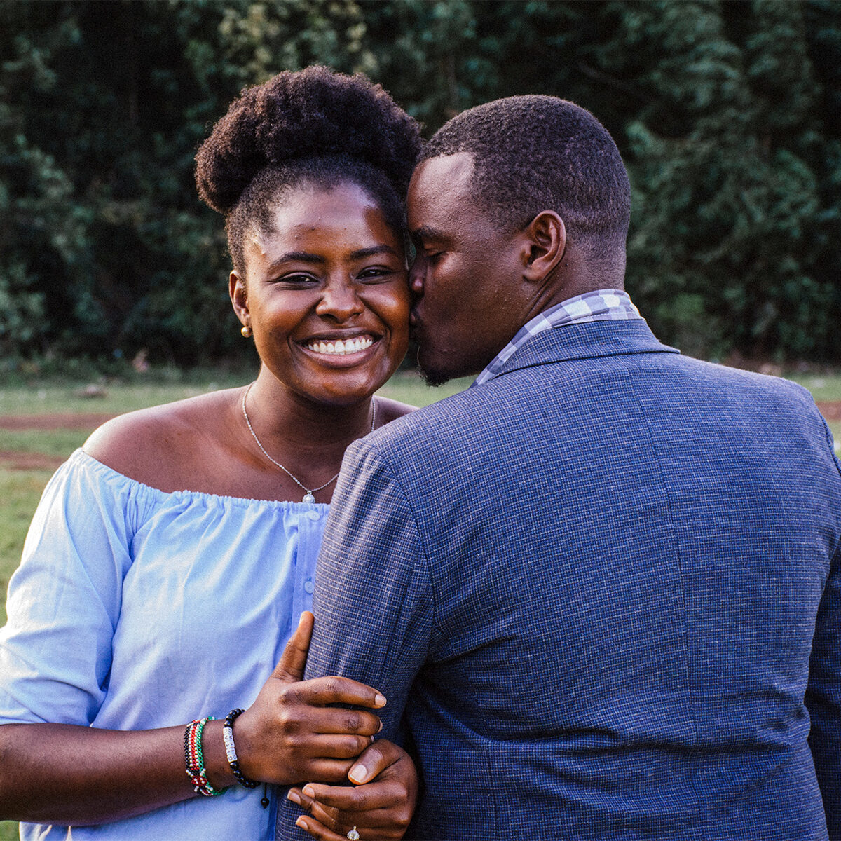 man kissing left cheek of smiling woman